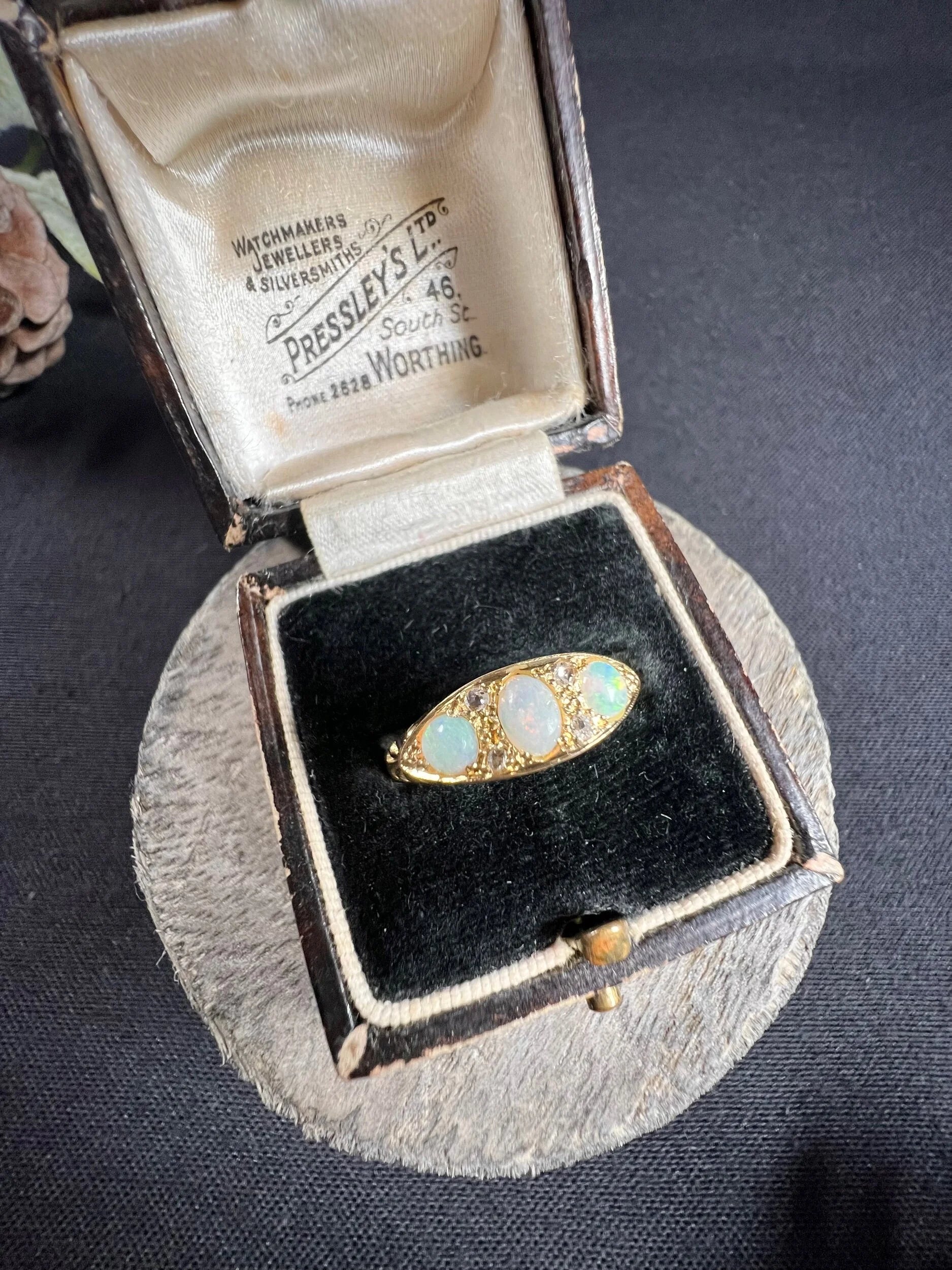 A boat-shaped gold ring with opals and diamonds, in a ring box