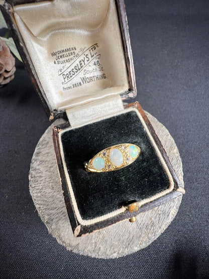 A boat-shaped gold ring with opals and diamonds, in a ring box