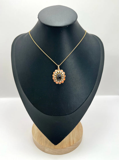 A cabochon garnet pendant with a seed pearl border in rose gold, with a chain, on a black bust