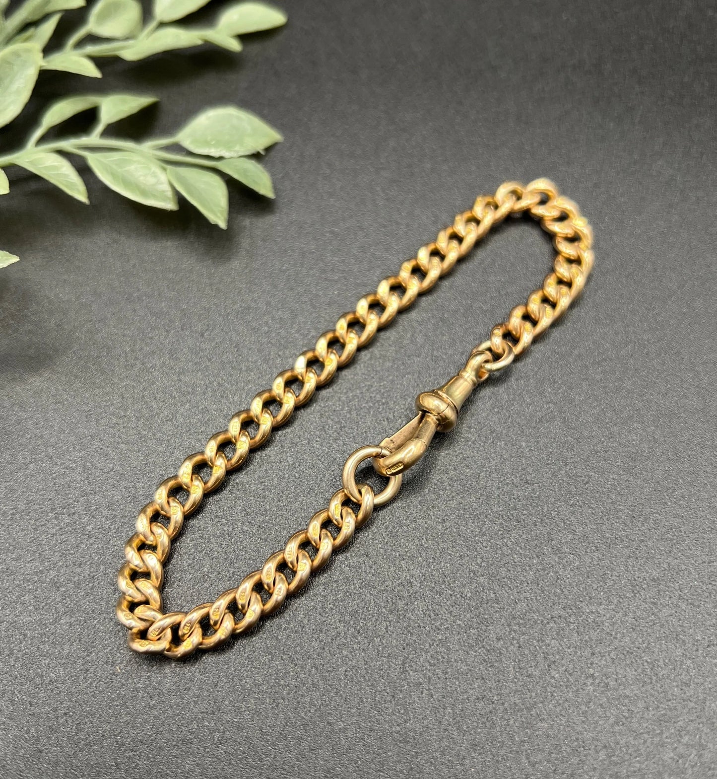 A gold curb link bracelet with a lobster claw clasp