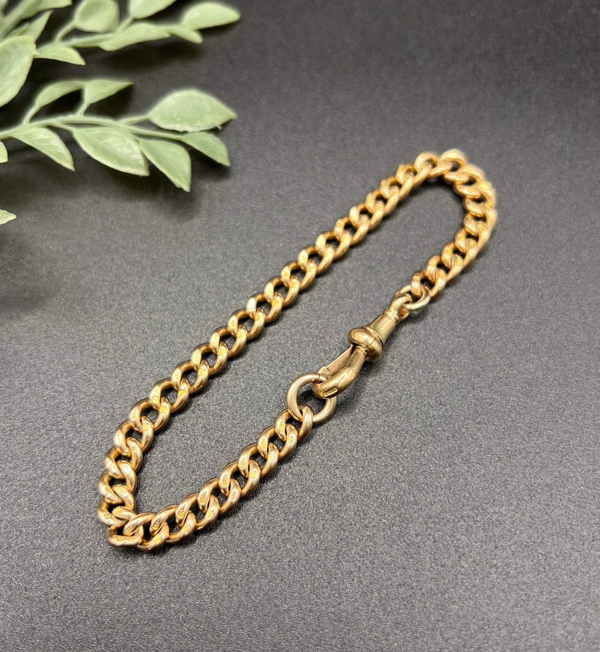 A gold curb link bracelet with a lobster claw clasp
