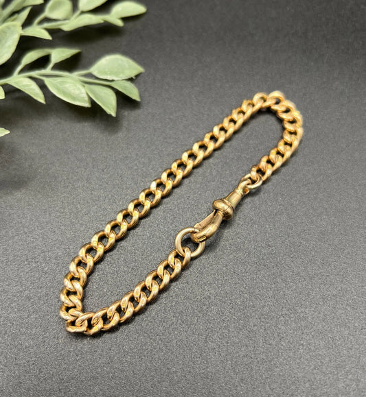 A gold curb link bracelet with a lobster claw clasp