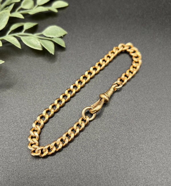 A gold curb link bracelet with a lobster claw clasp