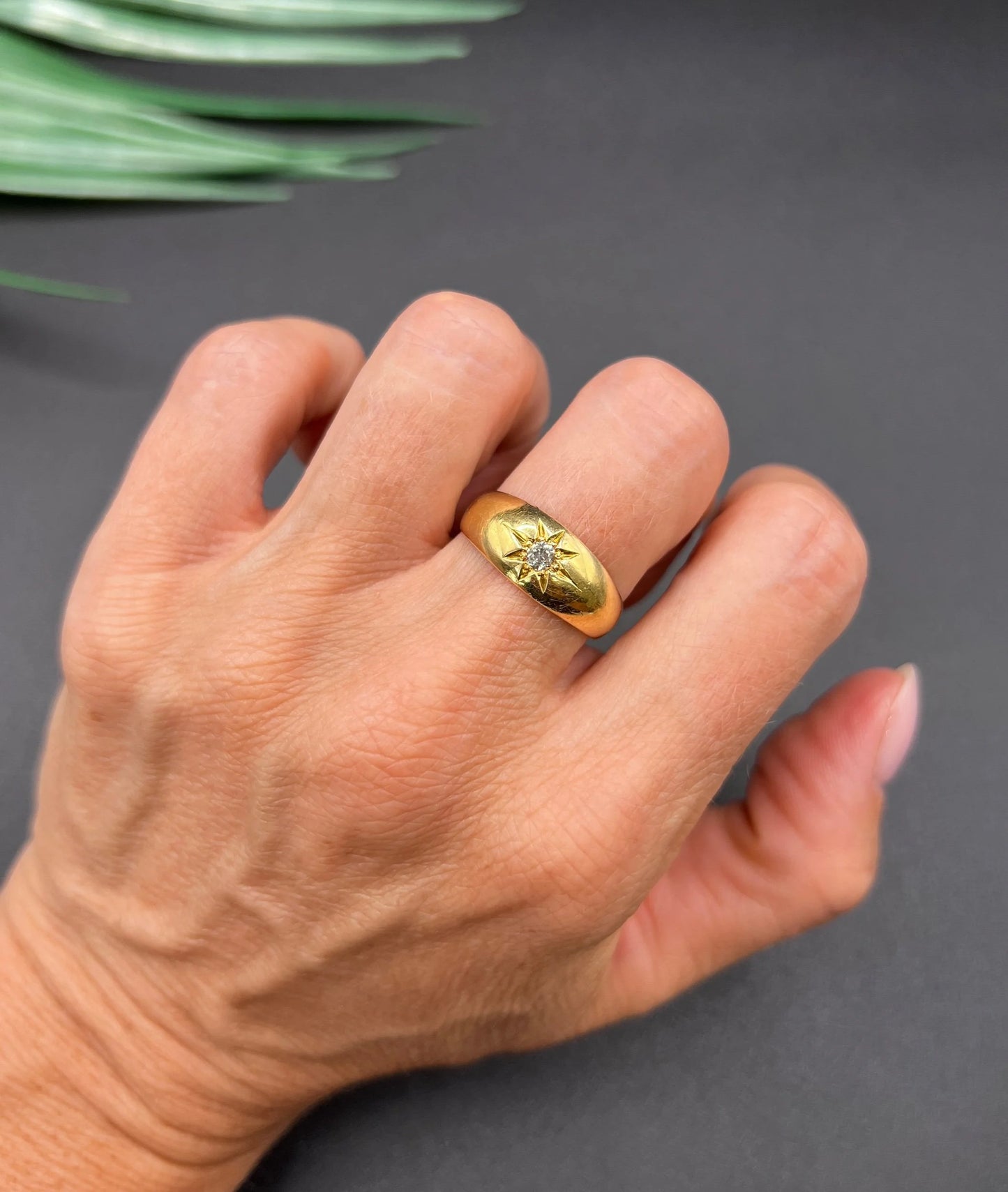 A single stone old cut diamond gypsy band ring in yellow gold, modelled on a hand
