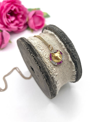 A fox head pendant in yellow gold with a ruby and diamond border, with a gold chain