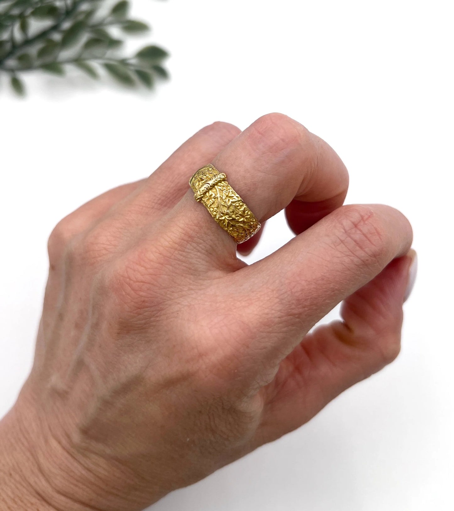A yellow gold ornate engraved buckle band ring, modelled on a hand