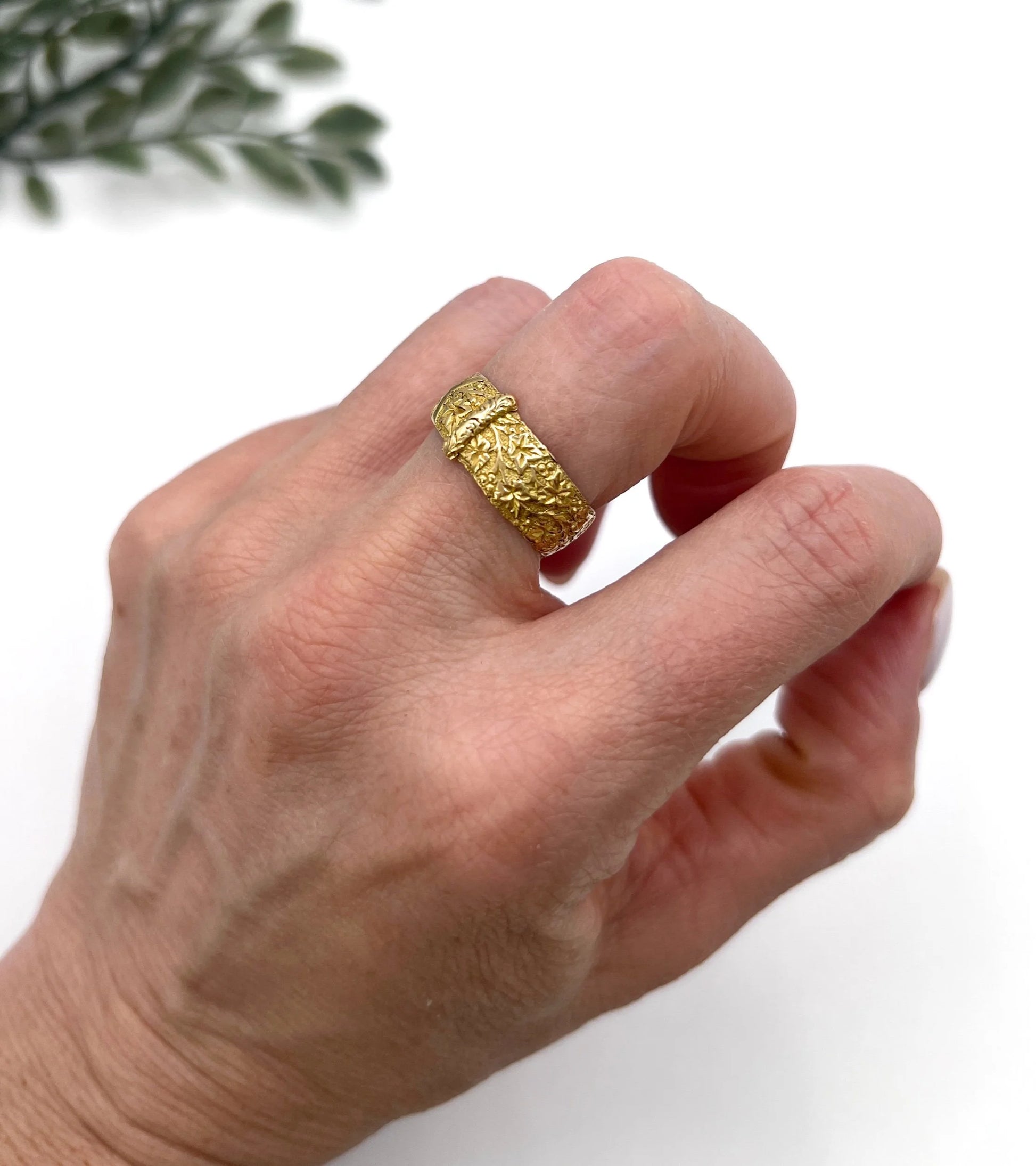 A yellow gold ornate engraved buckle band ring, modelled on a hand