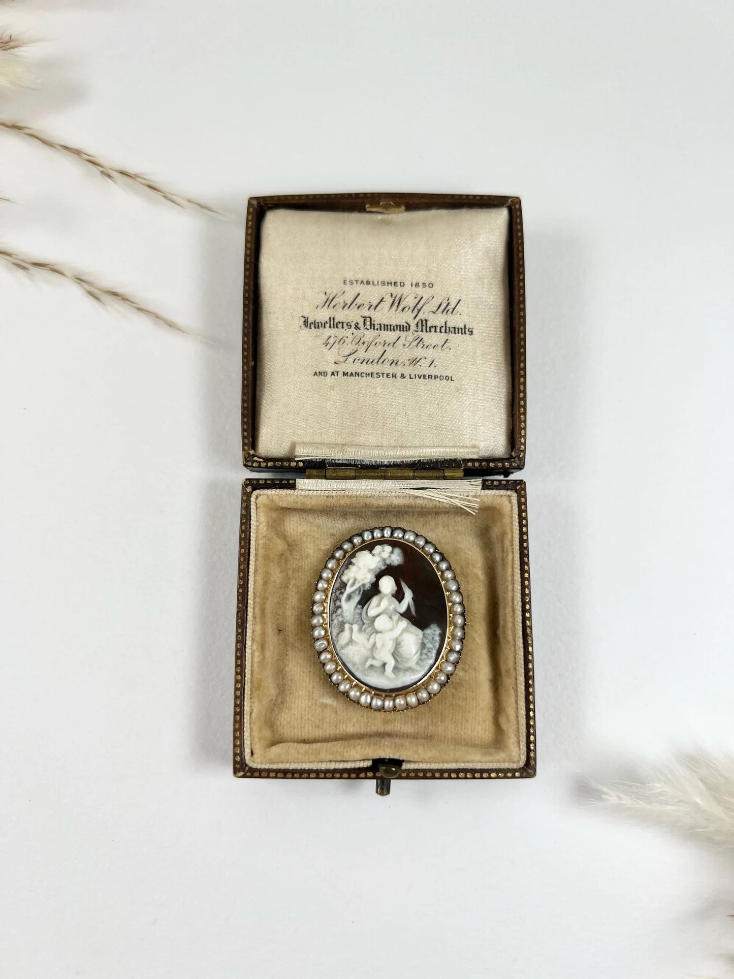 An antique oval cameo brooch depicting cherubs and birds, with a pearl border, set in gold