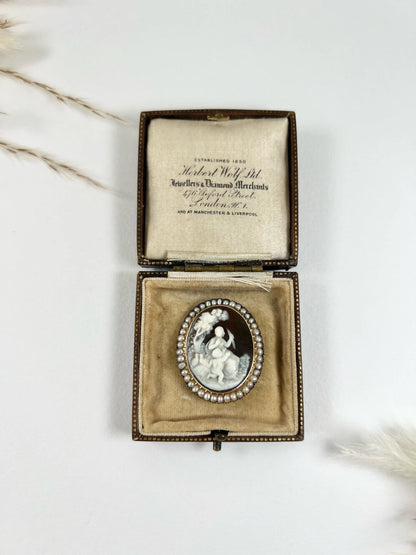 An antique oval cameo brooch depicting cherubs and birds, with a pearl border, set in gold