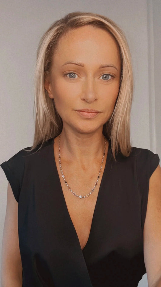 A coloured sapphire and diamond set necklace in platinum and gold, modelled by a lady wearing a black top