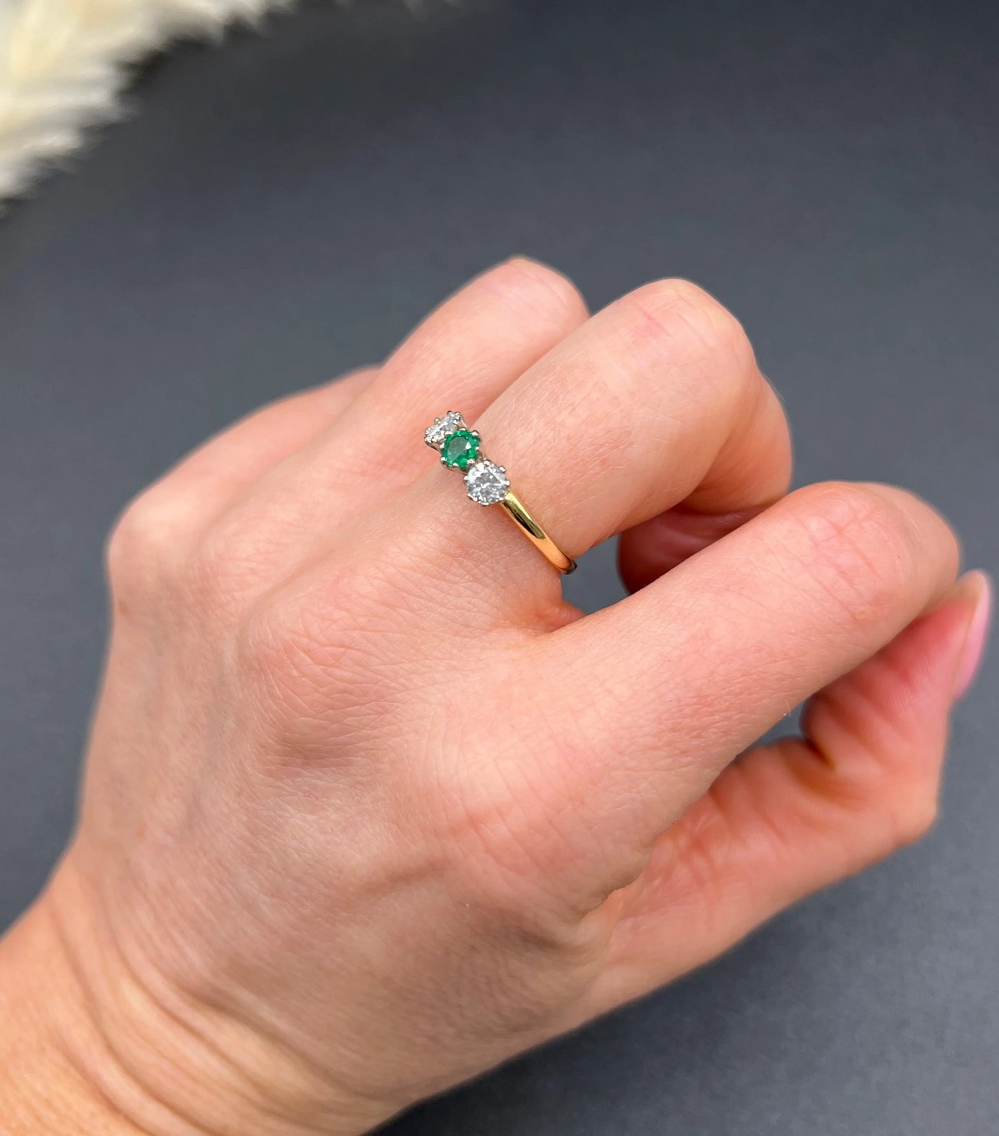 A three stone emerald and diamond ring in yellow gold and platinum, modelled on a hand