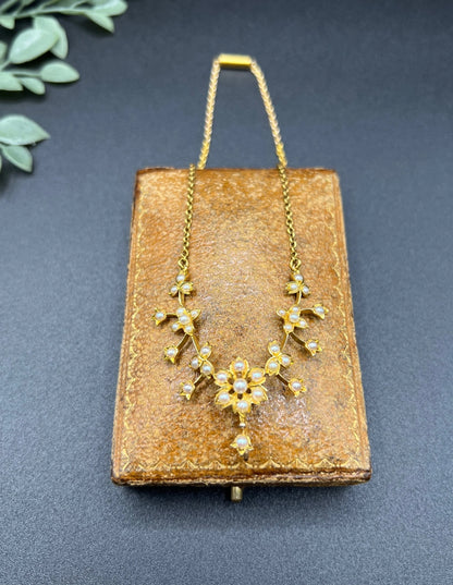 A yellow gold floral pendant necklace with seed pearls