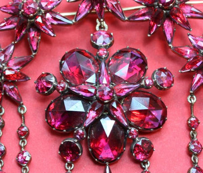 Antique Georgian Garnet and 18ct Gold Demi Suite; star earrings, cross pendant and large devant de corsage brooch, set with rose-cut garnets, Circa 1865.