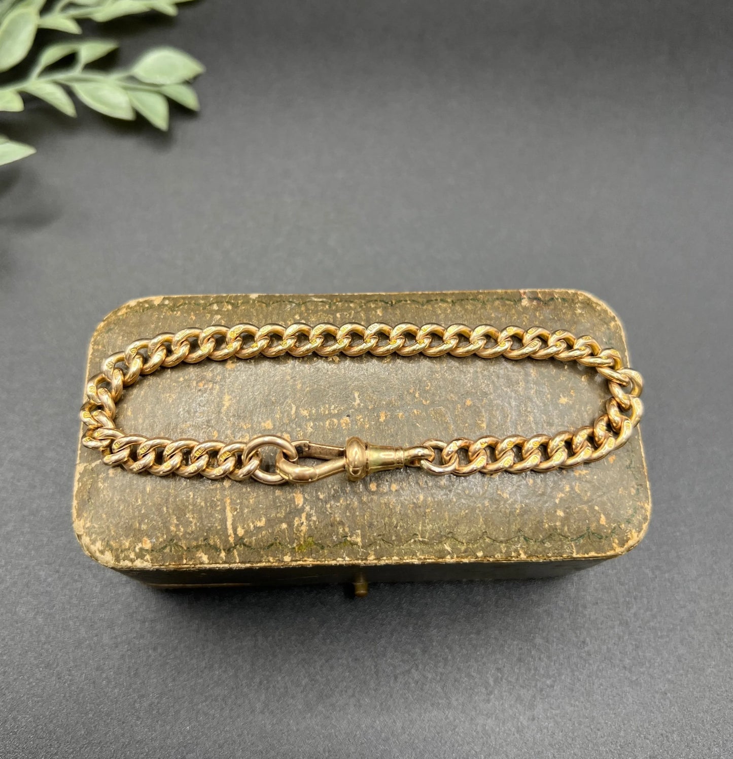 A gold curb link bracelet with a lobster claw clasp