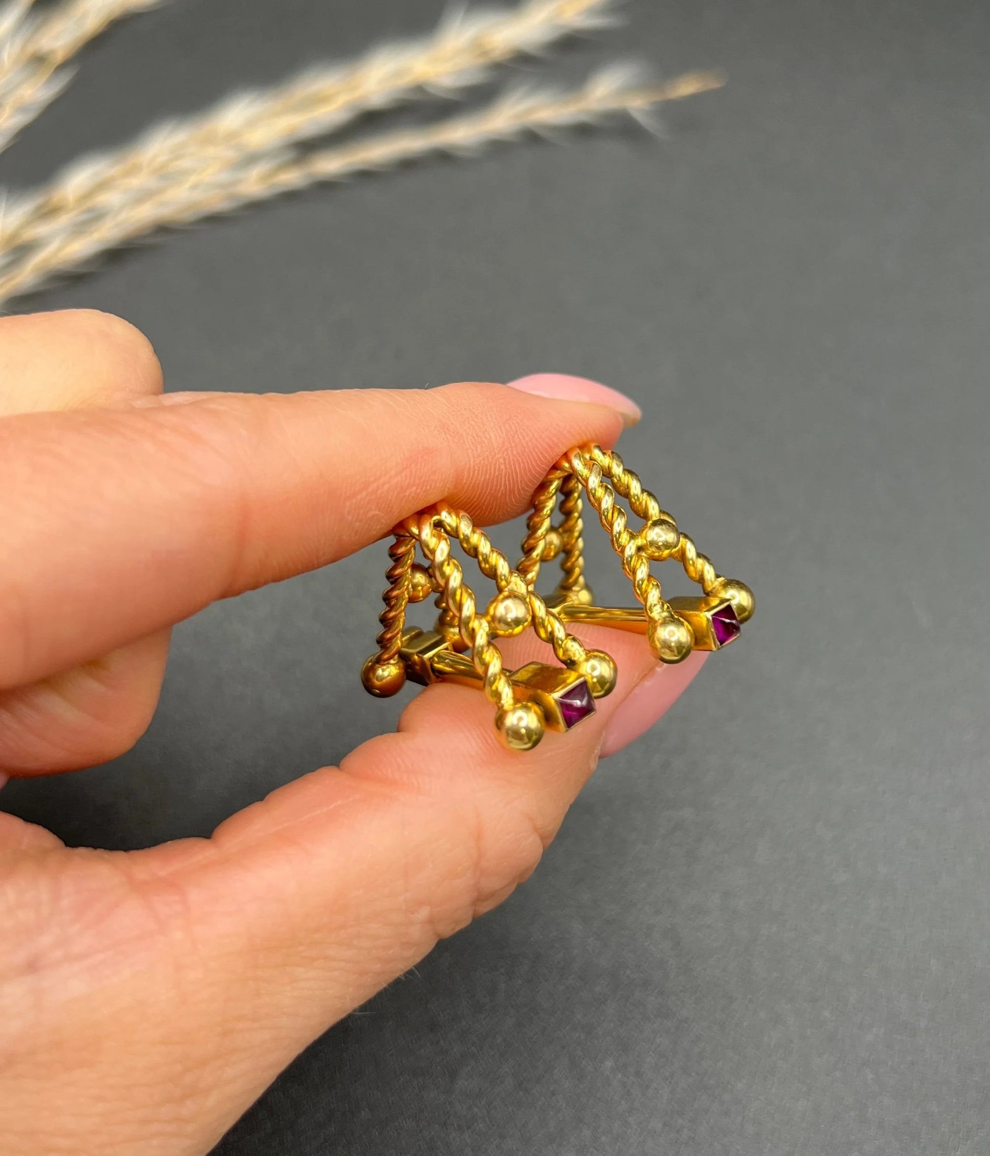 A pair of yellow gold ruby cufflinks, held in a hand