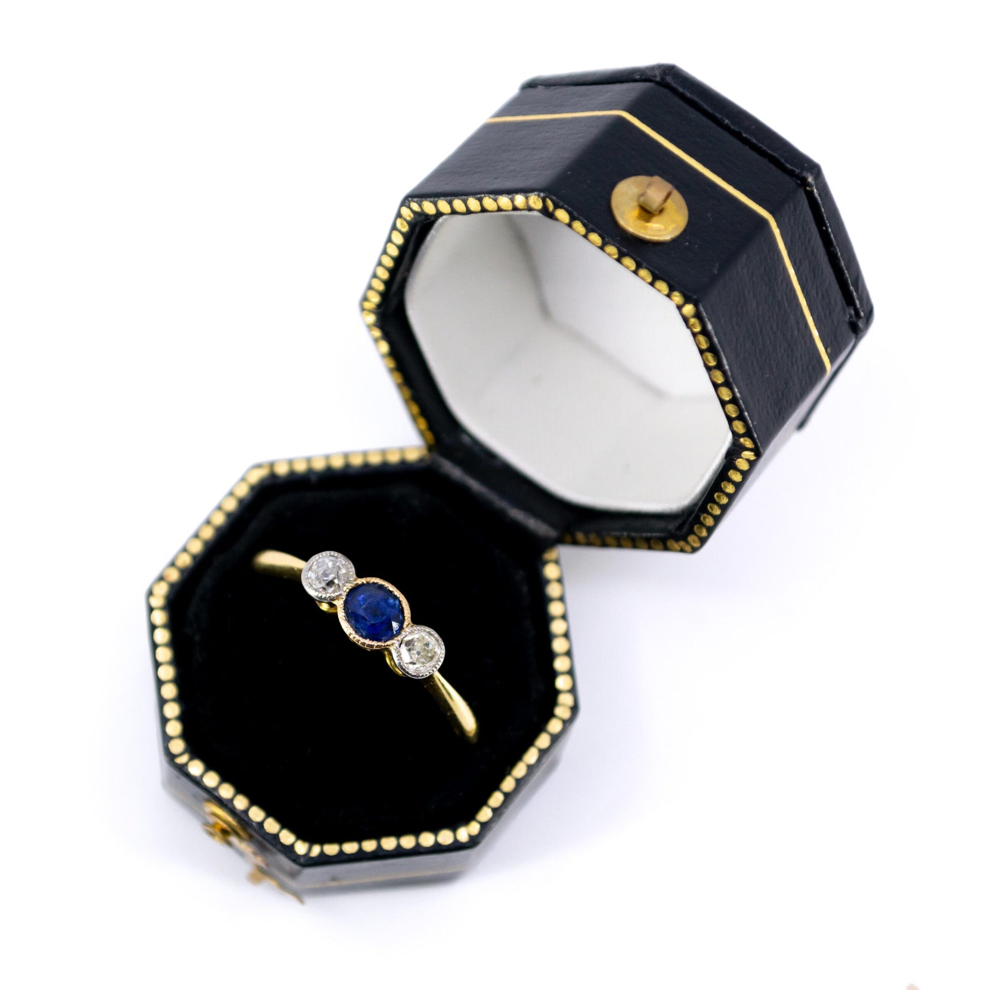 A three stone sapphire and diamond ring in yellow and white gold, in a ring box