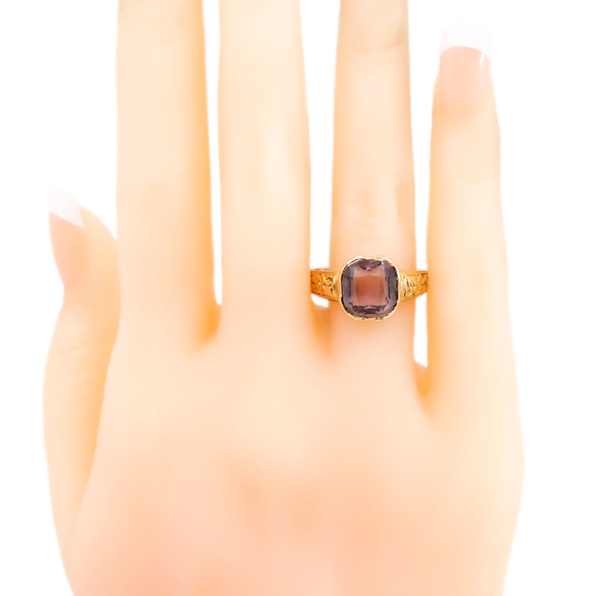 A solitaire amethyst ring in yellow gold with chased shoulders, modelled on a hand