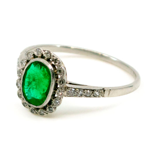 An oval emerald and diamond cluster ring in platinum
