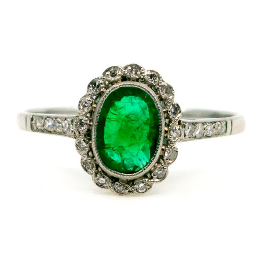 An oval emerald and diamond cluster ring in platinum
