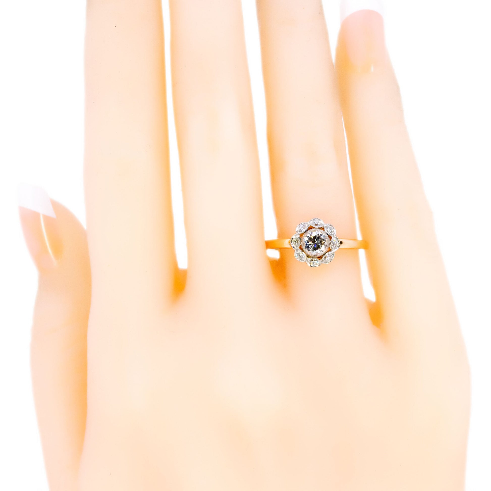 A round diamond cluster ring in gold and platinum, modelled on a hand