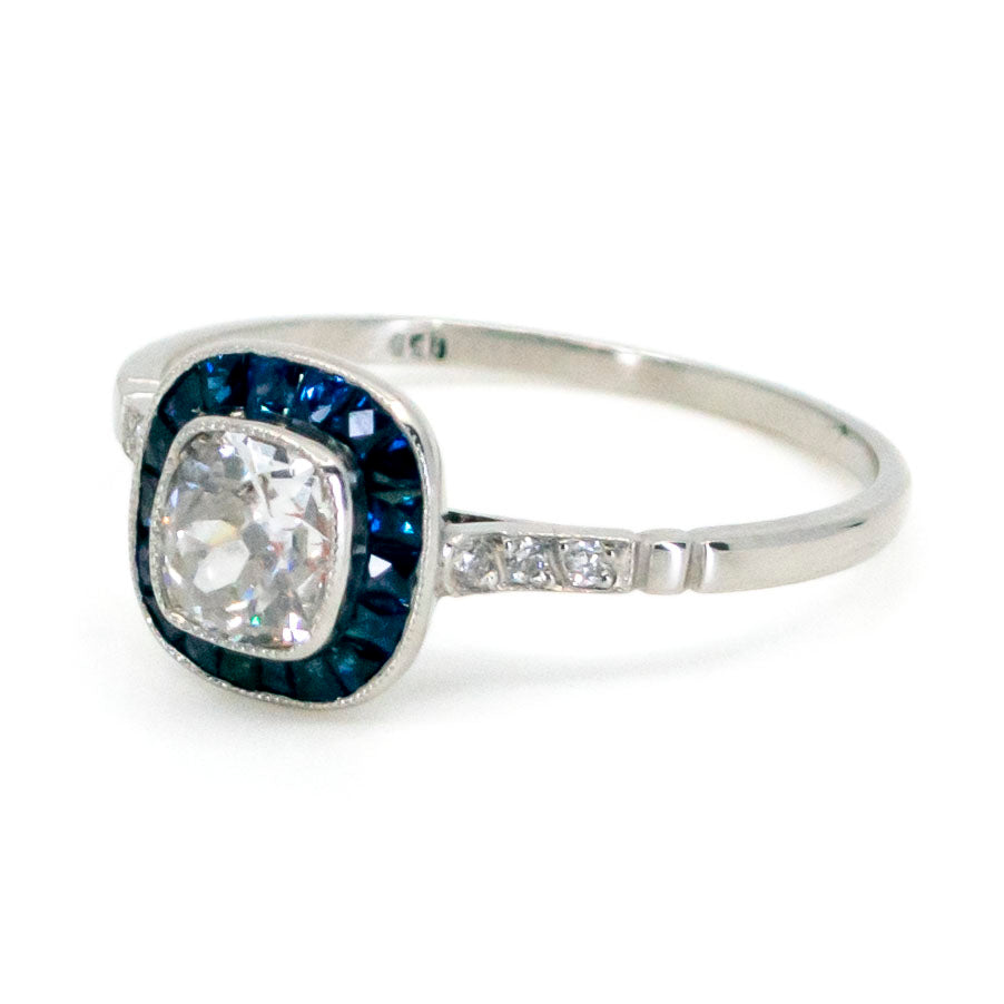 A cushion cut diamond halo cluster ring with sapphires in platinum
