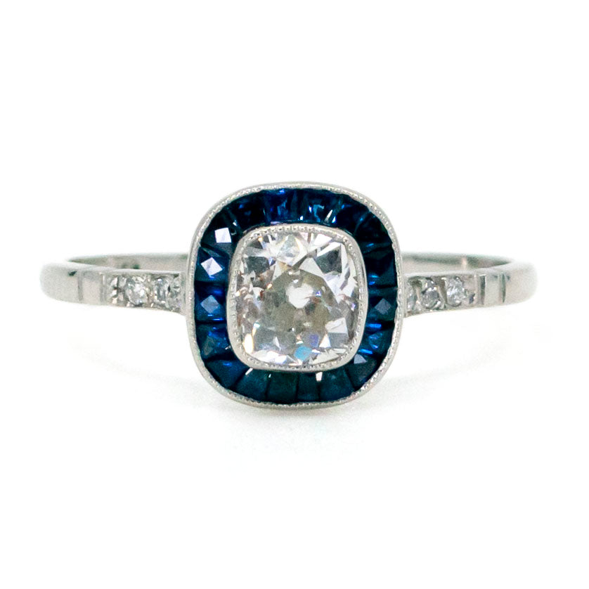 A cushion cut diamond halo cluster ring with sapphires in platinum