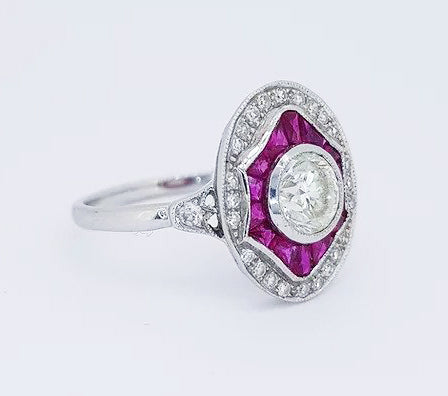 Diamond and Ruby Oval Cluster Dress Ring; 0.89 carat brilliant-cut diamond surrounded by calibre-cut rubies and an outer border of diamonds, 18ct white gold