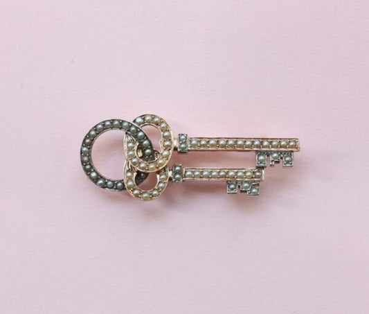 Antique Victorian Natural Pearl and 15ct Gold Key Brooch; two intertwined keys set with natural half pearls, and suspended from a keyholder. England, Circa 1880