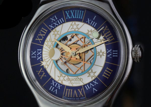 Swatch Tresor Magique Platinum 36mm Automatic Wrist Watch, golden face with celestial detailing, Roman numeral markers on outer blue band, blue leather strap, Circa 2000s