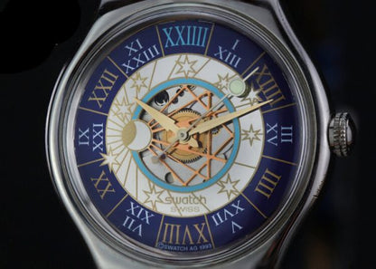 Swatch Tresor Magique Platinum 36mm Automatic Wrist Watch, golden face with celestial detailing, Roman numeral markers on outer blue band, blue leather strap, Circa 2000s