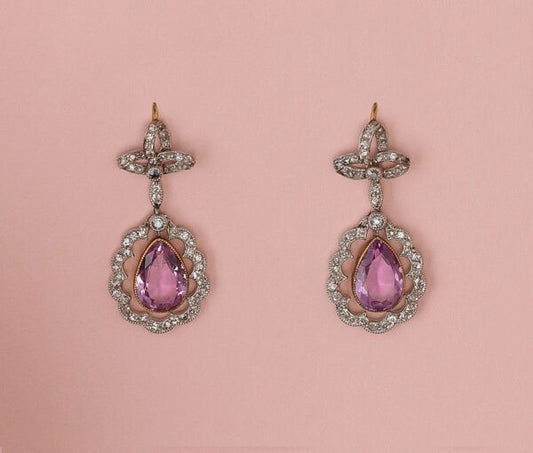 Antique Edwardian Pink Topaz and Diamond Cluster Drop Earrings; pear-cut faceted pink topaz within rose-cut diamond set surround suspended from bows set with rose cut diamonds, mounted in platinum and backed with gold. England, circa 1910
