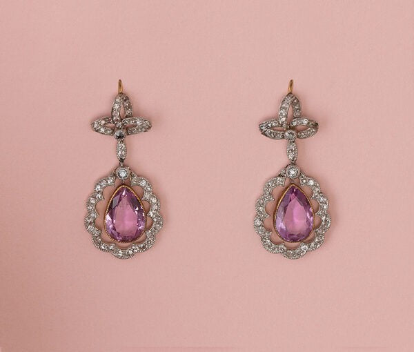 Antique Edwardian Pink Topaz and Diamond Cluster Drop Earrings; pear-cut faceted pink topaz within rose-cut diamond set surround suspended from bows set with rose cut diamonds, mounted in platinum and backed with gold. England, circa 1910