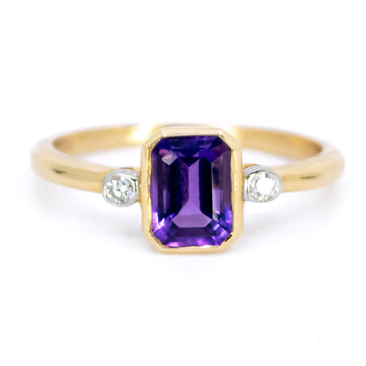 A three stone ring with amethyst and diamonds in yellow and white gold
