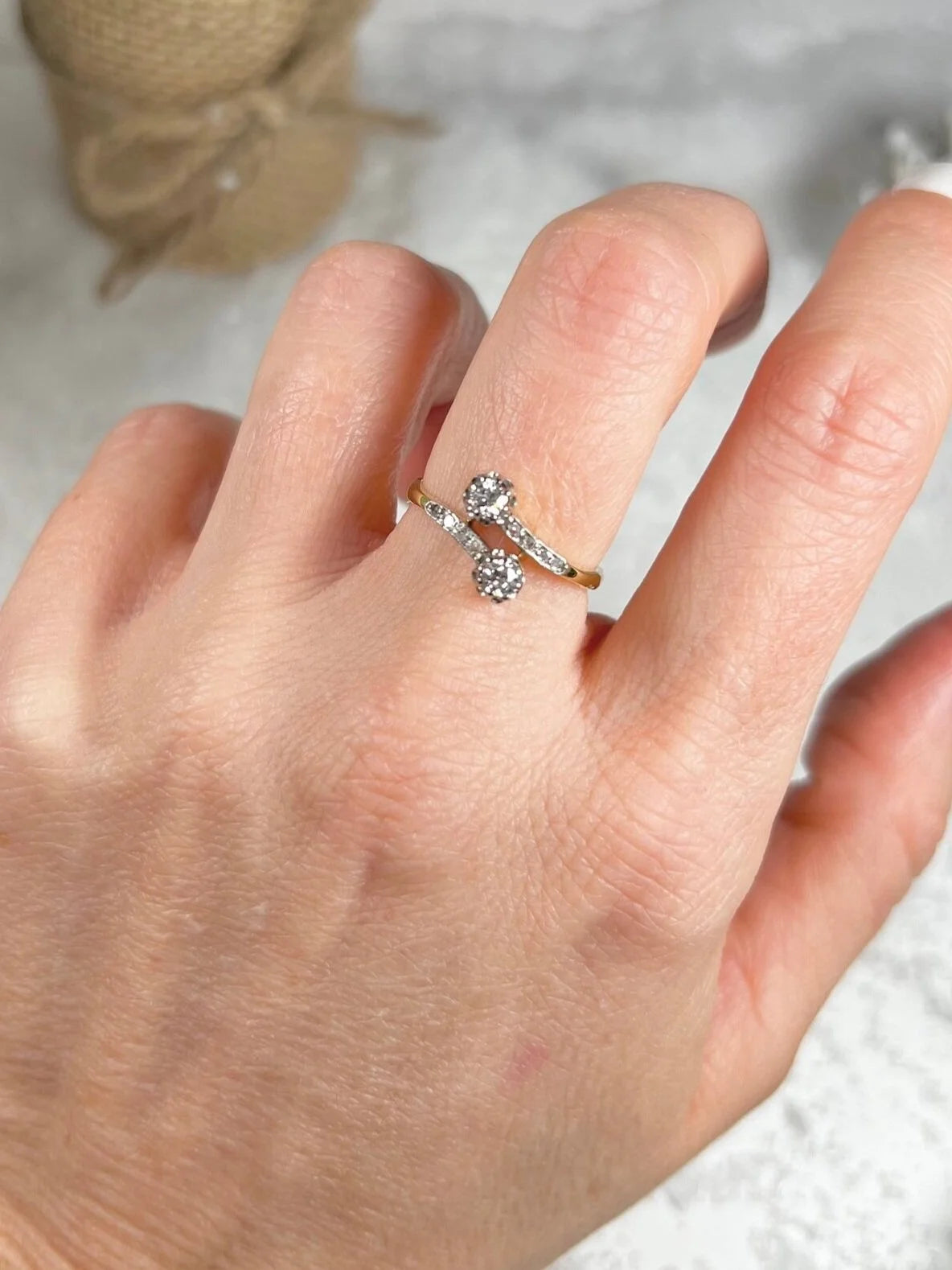 A two stone diamond crossover ring in yellow and white gold, modelled on a hand