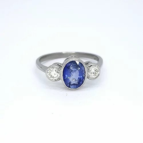1.25ct Sapphire and Diamond Three Stone Ring; central 1.25ct oval faceted sapphire flanked by 0.42cts brilliant cut diamonds, rubover settings in 18ct white gold
