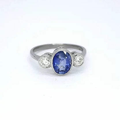 1.25ct Sapphire and Diamond Three Stone Ring; central 1.25ct oval faceted sapphire flanked by 0.42cts brilliant cut diamonds, rubover settings in 18ct white gold