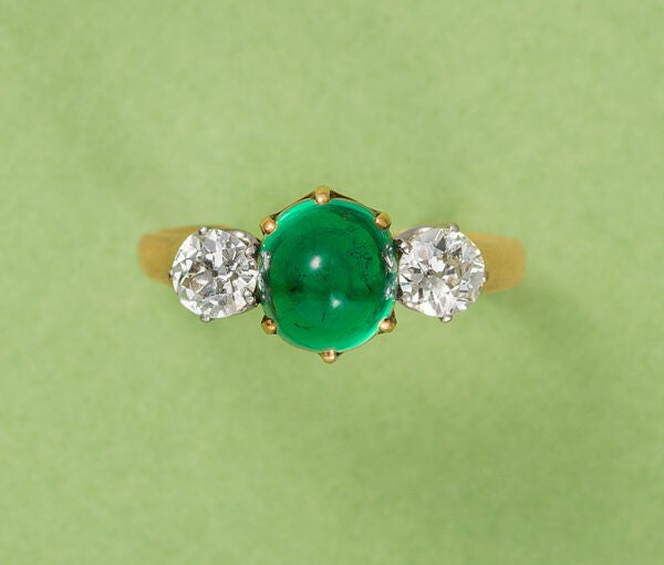 Antique Victorian 2ct Cabochon Emerald and Old Cut Diamond Three Stone Ring; 2ct high cabochon-cut emerald flanked by 0.65cts old-cut diamonds, in 18ct yellow gold. France, Circa 1900