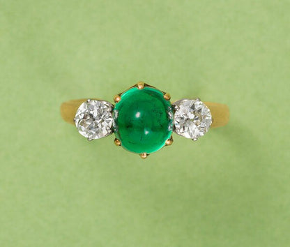 Antique Victorian 2ct Cabochon Emerald and Old Cut Diamond Three Stone Ring; 2ct high cabochon-cut emerald flanked by 0.65cts old-cut diamonds, in 18ct yellow gold. France, Circa 1900