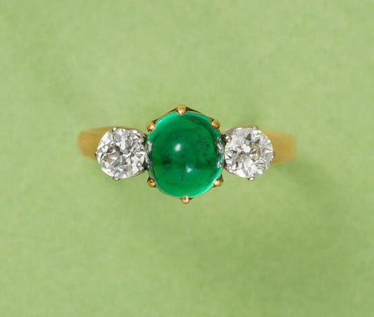 Antique Victorian 2ct Cabochon Emerald and Old Cut Diamond Three Stone Ring; 2ct high cabochon-cut emerald flanked by 0.65cts old-cut diamonds, in 18ct yellow gold. France, Circa 1900