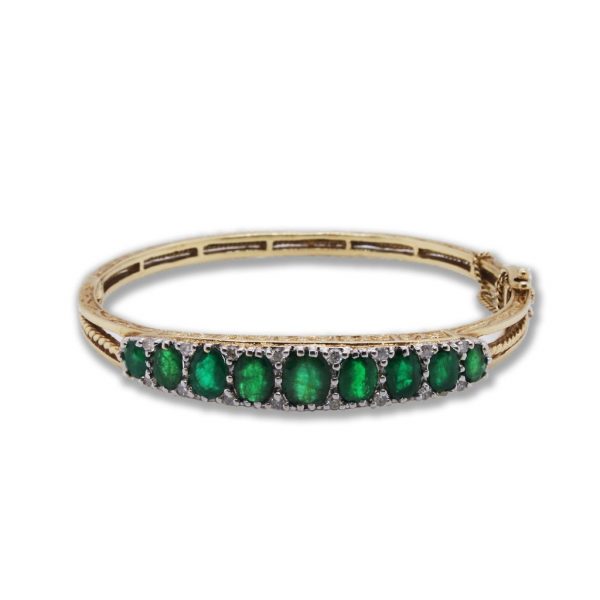 Vintage Emerald and Diamond Bangle; ornately carved hinged bangle, set with nine graduated emeralds, 9.00cts, diamond surround, 9ct yellow gold, with safety chain and clasp
