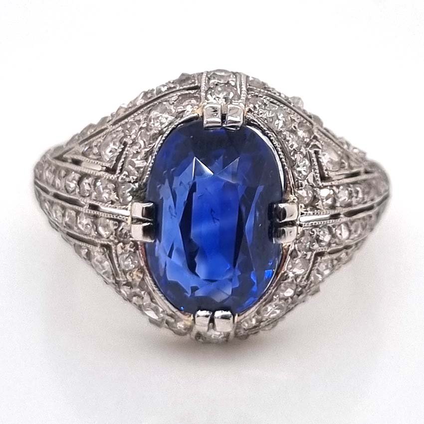 Late Art Deco 5ct Sapphire and Diamond Cluster Bombe Ring, 5.13ct oval sapphire in domed single-cut diamond studded surround in platinum