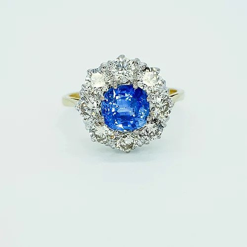Sapphire and Diamond Cluster Ring; 1.30 carat circular sapphire surrounded by eight diamonds, 1.80 carat total, in 18ct gold