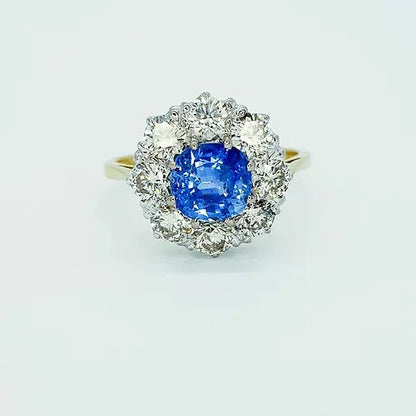 Sapphire and Diamond Cluster Ring; 1.30 carat circular sapphire surrounded by eight diamonds, 1.80 carat total, in 18ct gold