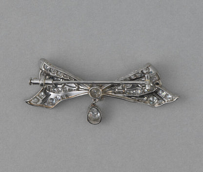 Antique Edwardian Old Cut Diamond and Platinum Bow Brooch, with 0.30ct pear shaped diamond drop, 1.30 carat total. Netherlands, circa 1915