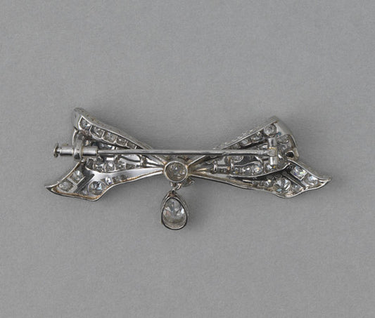 Antique Edwardian Old Cut Diamond and Platinum Bow Brooch, with 0.30ct pear shaped diamond drop, 1.30 carat total. Netherlands, circa 1915