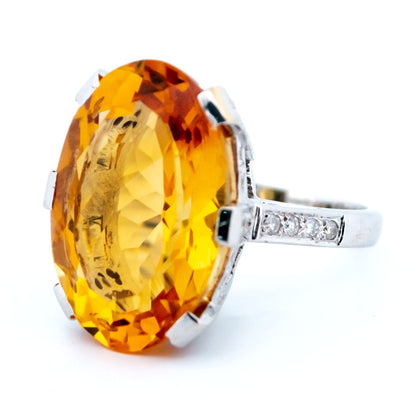A large statement ring featuring an oval citrine with diamond shoulders in white gold