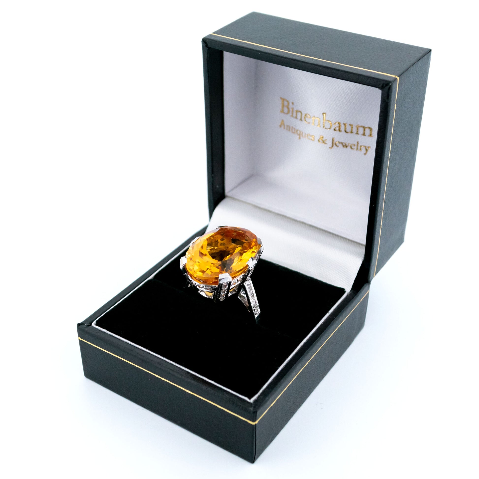 A large statement ring featuring an oval citrine with diamond shoulders in white gold, in a ring box
