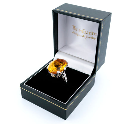 A large statement ring featuring an oval citrine with diamond shoulders in white gold, in a ring box