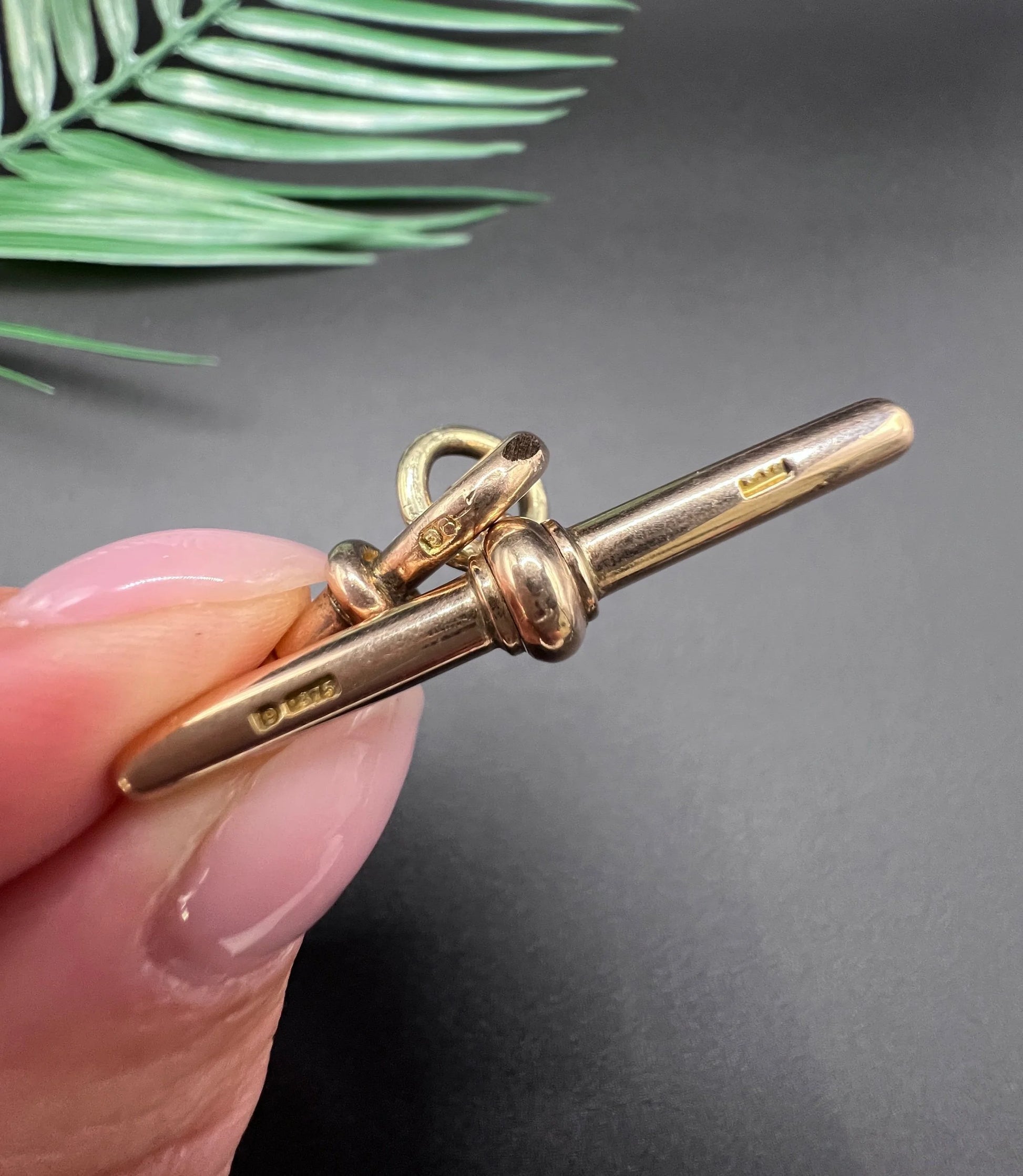 Close-up of stamps on a rose gold T-bar and dog clip