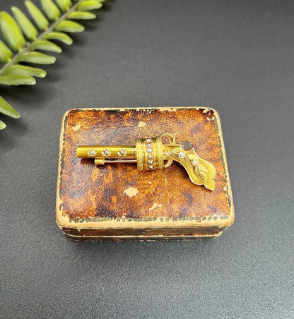 A yellow gold novelty gun brooch with diamonds and seed pearls